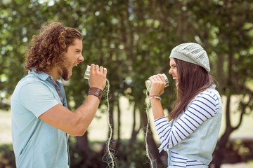 Obraz premium Young couple shouting through tin cans