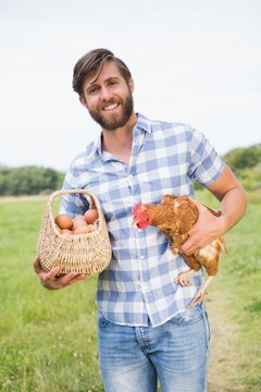 Happy farmer holding chicken and eggs