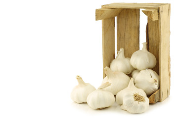 garlic bulbs in a wooden crate on a white background