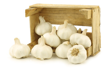 garlic bulbs in a wooden crate on a white background