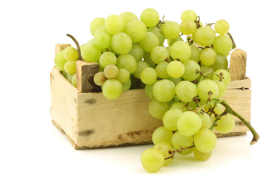 fresh white seedless grapes on the vine in a wooden crate