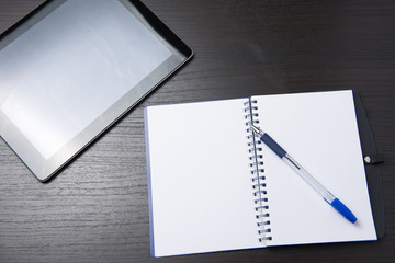 tablet with notebook and pen on dark table
