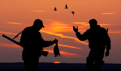 Papier Peint photo autocollant Chasser deux chasseurs au coucher du soleil
