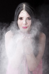 Portrait of a woman blowing a white powder