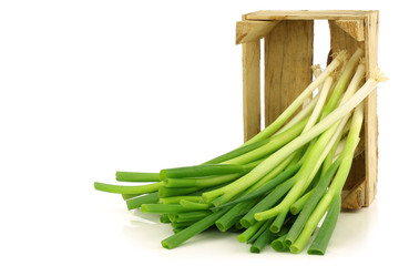 fresh green onions in a wooden crate on a white background