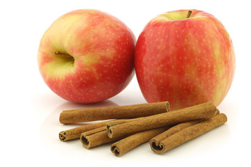 dried cinnamon sticks,  fresh apples on a white background