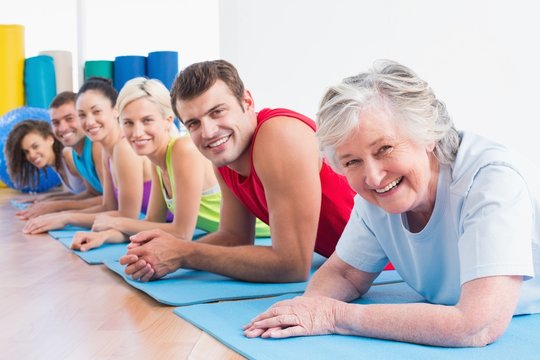 Senior woman with friends lying on exercise mats at gym