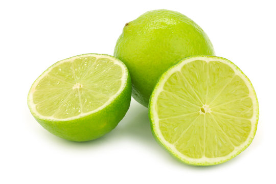 one whole lime fruit and two halves on a white background
