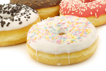 assorted colorful glazed donuts with sprinkles on a white backgr