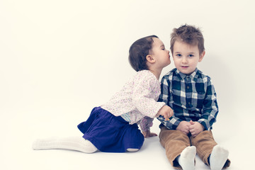 little girl kissing her older brother on the cheek isolated