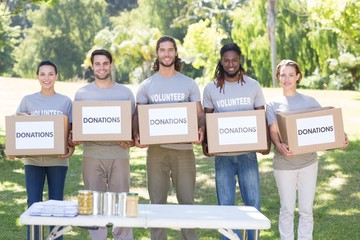 Happy volunteers with donation boxes in park