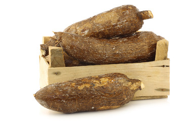 cassava roots in a wooden crate on a white background