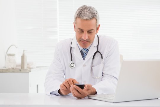 Smiling doctor using his phone