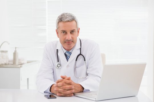 Smiling doctor sitting at his desk