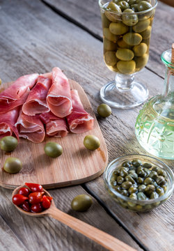 Jamon with capers and olives on the wooden board