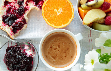 Tray with bread with jam, fruits, orange and cup of coffee