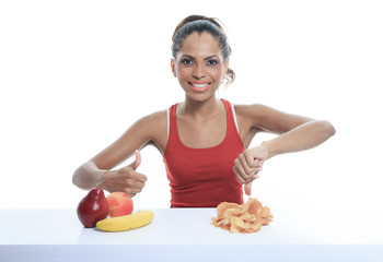 beautiful young woman choosing between fruits and potato chips