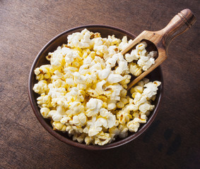 Fresh popcorn in bowl on wooden table