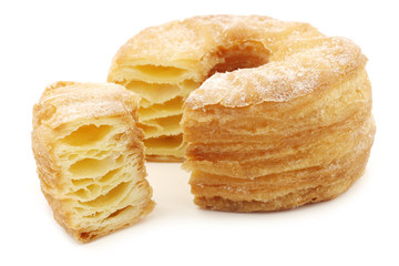sugared puff pastry donut with a cut piece on a white background