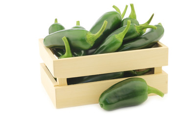 fresh green peppers in a wooden box (capsicum) on a white backgr