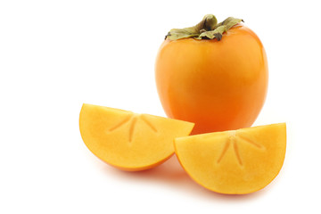 fresh kaki fruit and some cut pieces on a white background