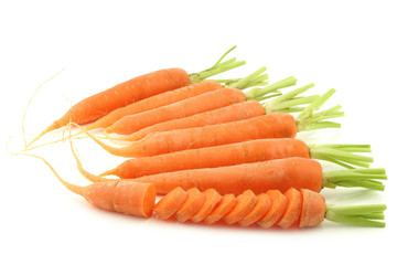 freshly harvested carrots and a cut one on a white back
