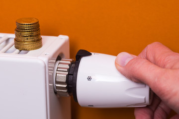 Radiator thermostat, coins and hand - brown