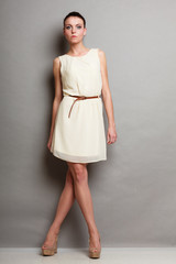 Glamour girl in white dress on gray