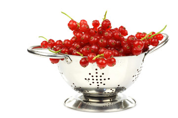 metal colander with a bunch of red currant on a white background