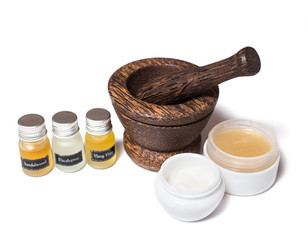 Wooden pounder with bottles of organic oils and cream isolated