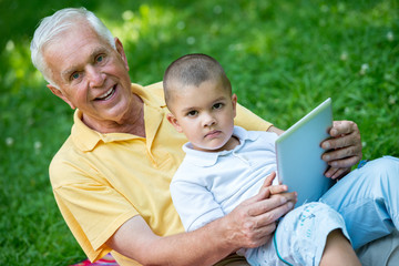 grandfather and child in park using tablet
