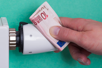 Radiator thermostat, banknote and hand - aqua