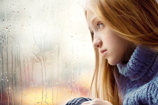 Rainy Day: Girl looking through the Window