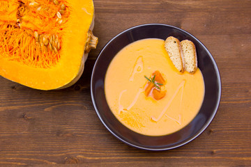 Cream of pumpkin soup and ingredients on wood from above