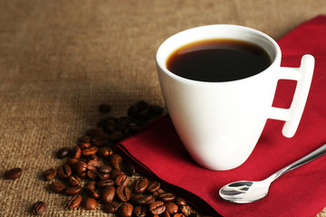 Cup of coffee with beans on rustic wooden background