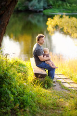 Obraz premium Father with his little baby sitting on wooden bench
