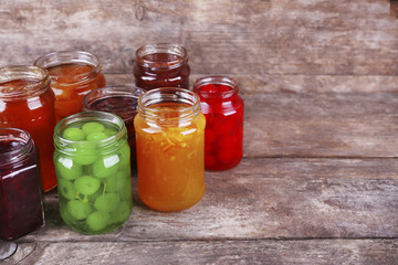 Homemade jars of fruits jam on rustic wooden background