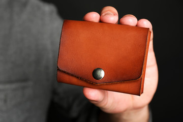 Man holding hand made leather wallet on black background