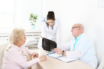 Happy doctors and patient in hospital clinic