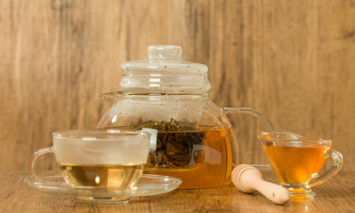 Glass cup and teapot with green tea with honey