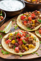 tortillas with chili con carne and tomato salsa on wooden board