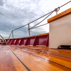 Wood deck of a sailboat at sea under stormy skies. Square format