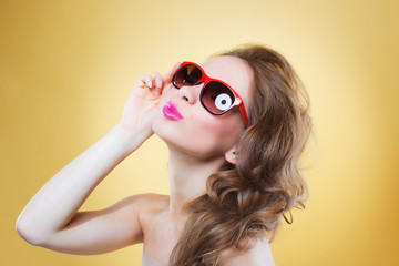 Attractive surprised young woman wearing sunglasses on gold back