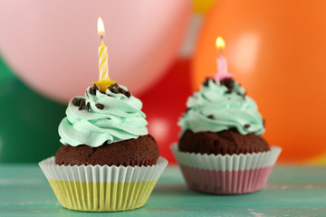 Delicious birthday cupcakes on table on bright background