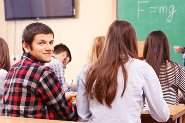 Group of students sitting in classroom and  listening teacher