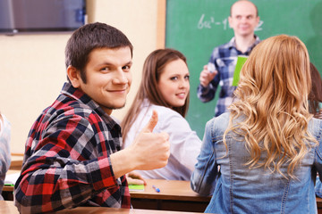 Group of students sitting in classroom and  listening teacher