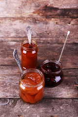 Jars of tasty jam on wooden background