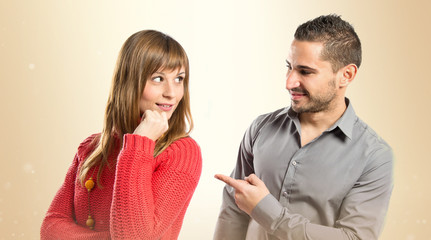 Man pointing his girlfriend over white background