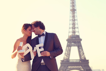 bride and groom holding LOVE letters near Eiffel Tower