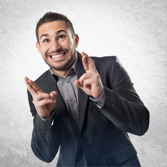 Young businessman with his fingers crossing over white backgroun